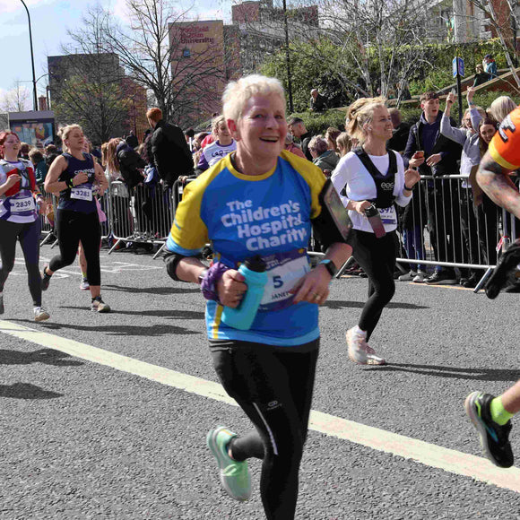 An older woman runs as part of a crowd. She wears a t-shirt that reads 